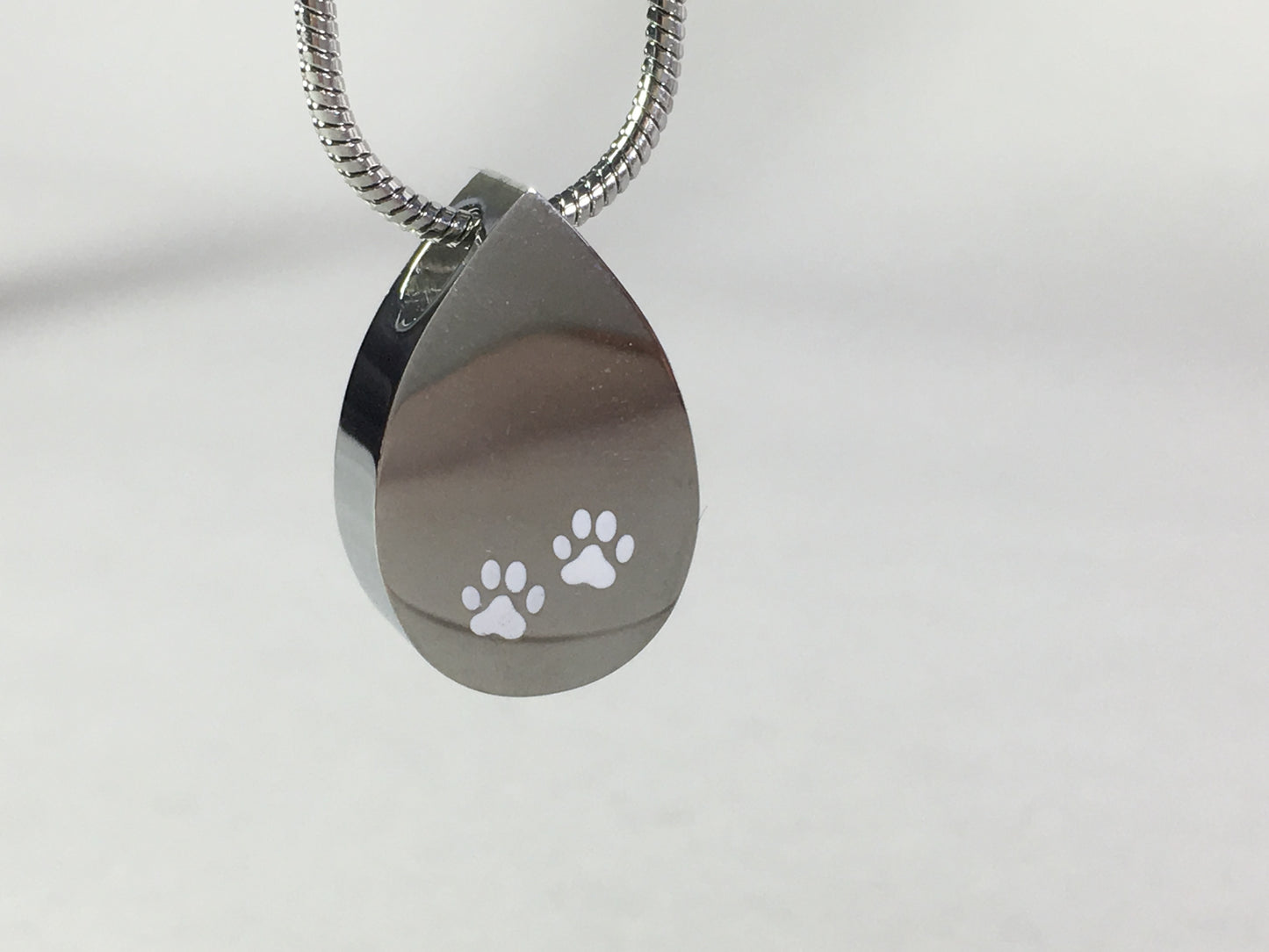Cremation Jewellery Necklace with a tear drop shaped pendant with white paw prints design