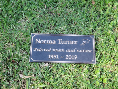 bronze plaque with memorial inscription for a person. The plaque is laying on a bed of grass