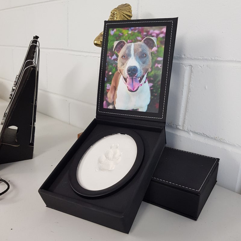 A display case with a photo of a dog and a paw print impression in clay